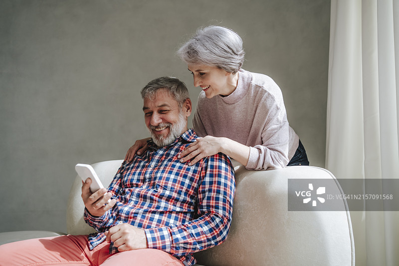 中年妇女在家靠在男人身上，通过智能手机进行视频通话图片素材