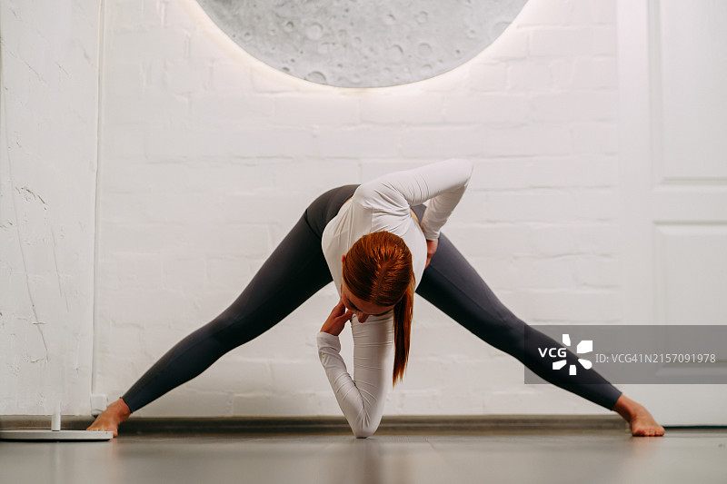 美丽的红发女教练在月亮背景下做瑜伽图片素材