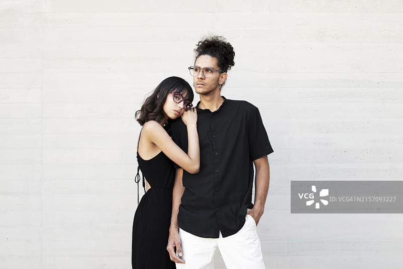 年轻女人靠在男人肩膀上，站在白墙前图片素材