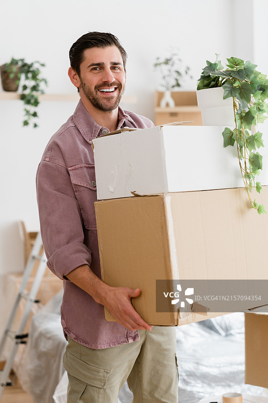 快乐的男人抱着纸箱搬进新公寓图片素材