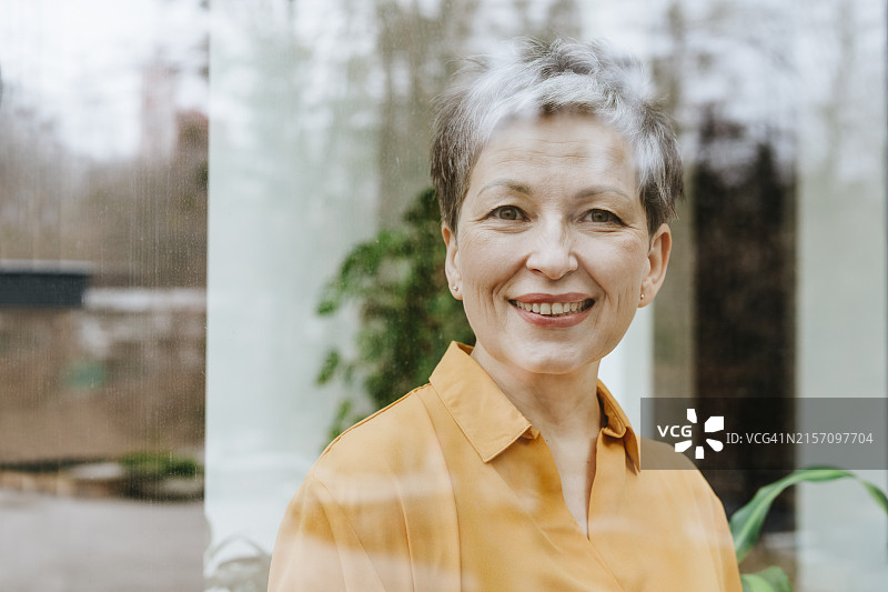 透过玻璃看到的快乐的中年女商人图片素材