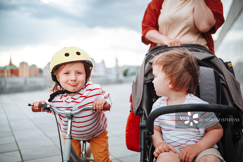 家庭出游：妈妈带着两个孩子在城市滨水区散步图片素材