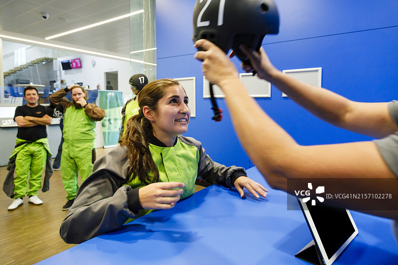 接待员帮助女士在室内跳伞中心佩戴头盔图片素材