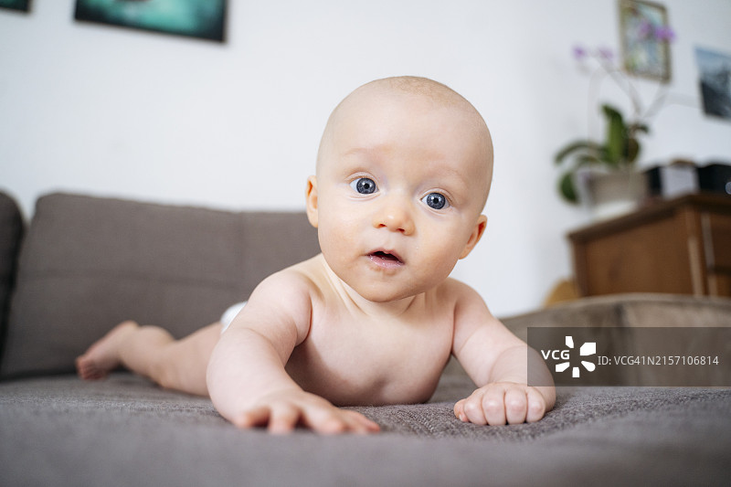 可爱的无上衣幼儿男孩躺在沙发上图片素材