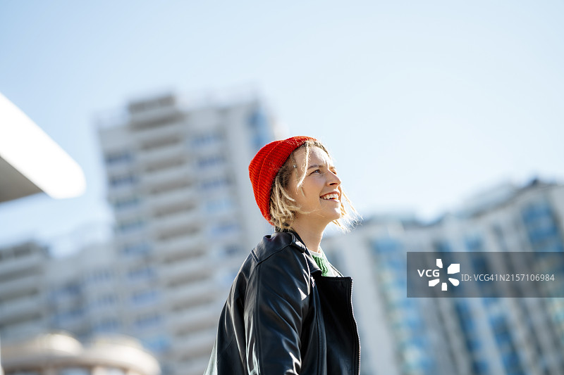 微笑的年轻女子在阳光明媚的日子里戴着针织帽图片素材