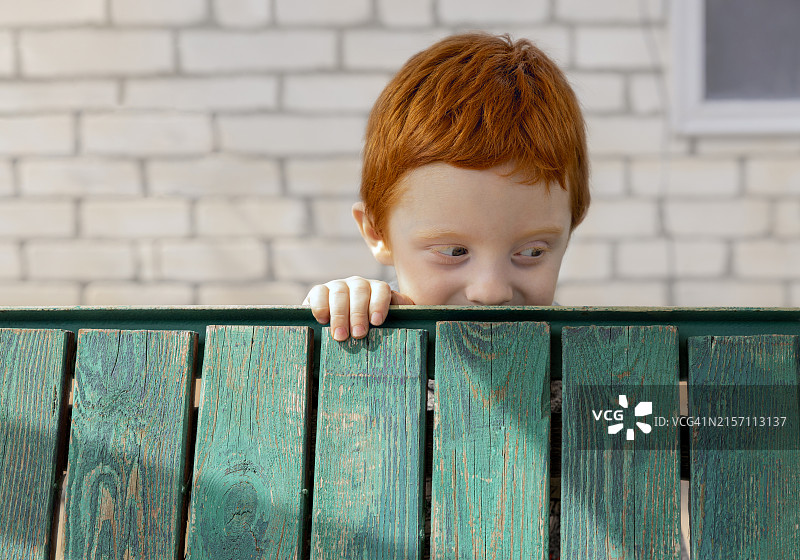绿木板后面的红发男孩图片素材