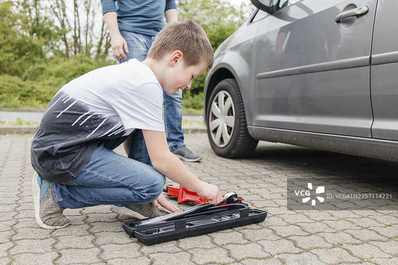 男孩从汽车旁的工具箱里拿起扳手图片素材