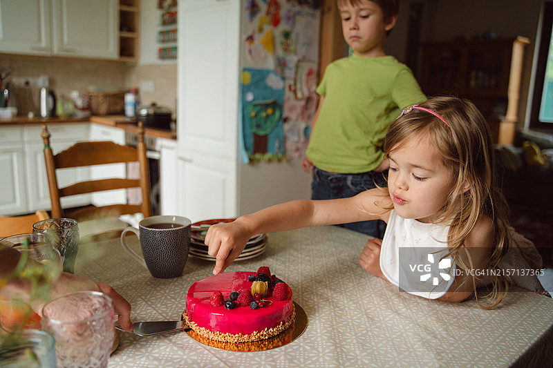 孩子们在厨房桌子上兴奋地切粉色浆果蛋糕图片素材