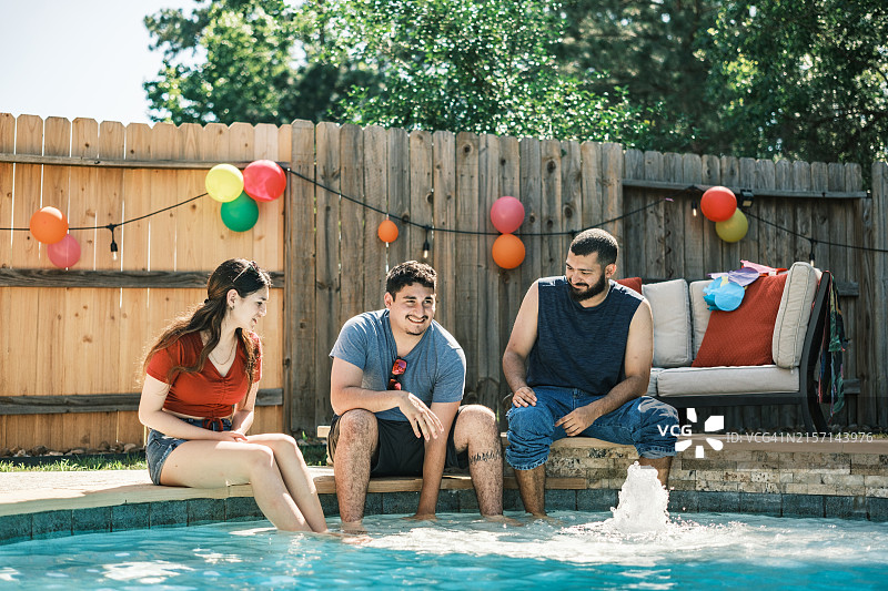 在后院派对泳池里享受的年轻拉丁裔人图片素材