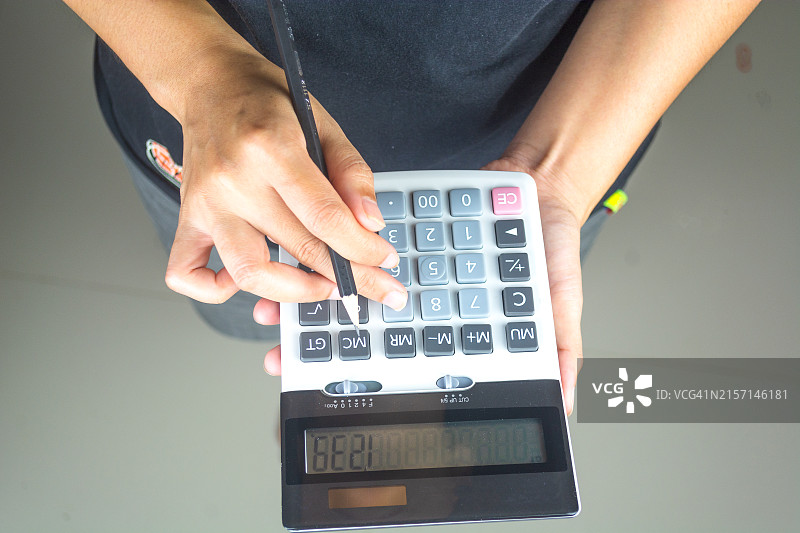 女商人手持钢笔使用计算器，在家中办公室计算财务支出图片素材