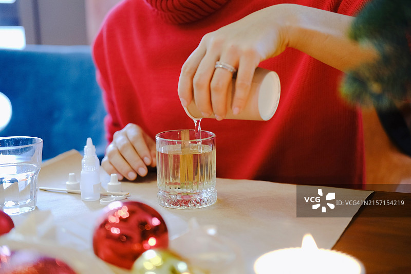 将融化的蜡倒入量杯中，保持在手工制作的秤上图片素材