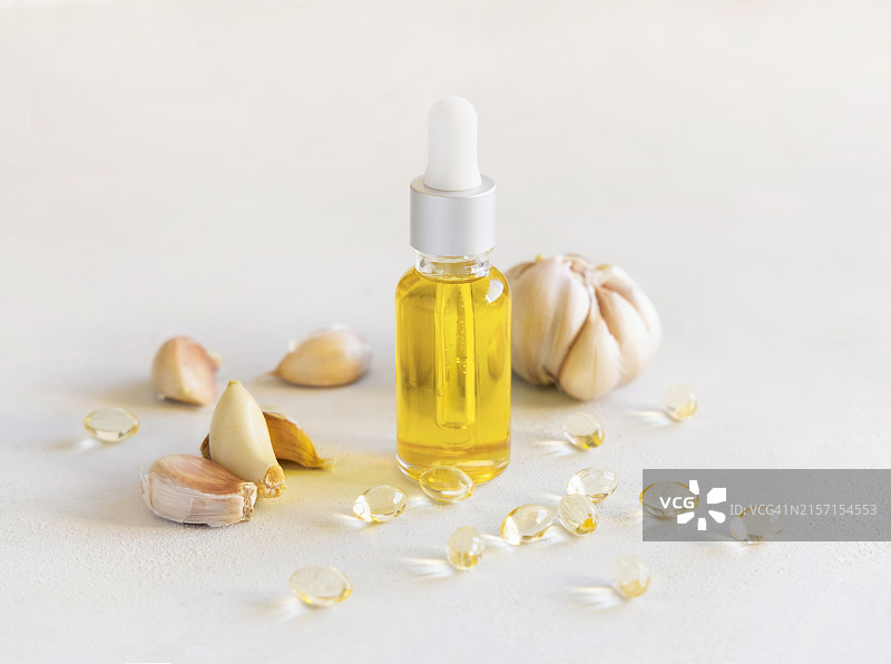 白桌上蒜油瓶和蒜瓣图片素材