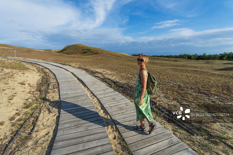 在立陶宛内林加库罗尼亚沙嘴的灰色沙丘上行走的女人图片素材