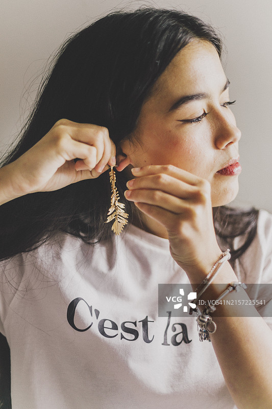 年轻女人戴上金色耳环图片素材
