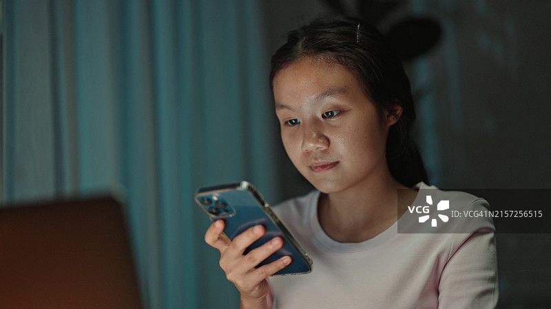 青少年学生在晚上用智能手机与语音助手交谈图片素材