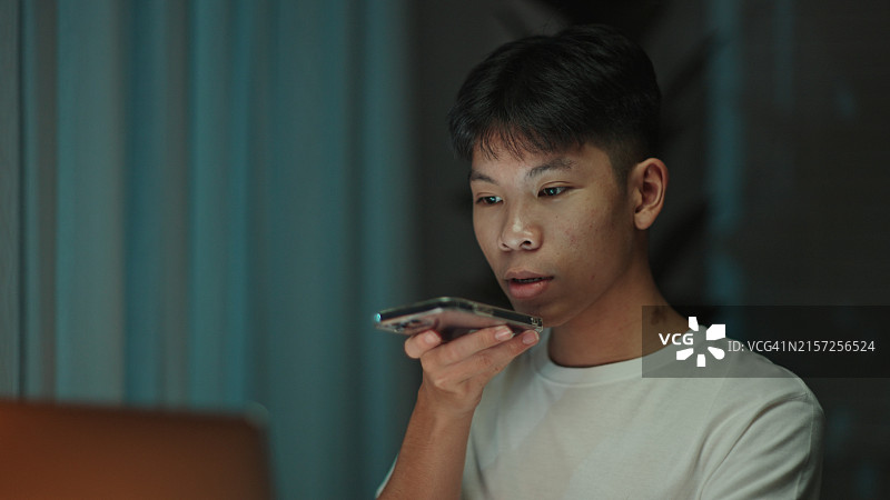 青少年学生在晚上用智能手机与语音助手交谈图片素材