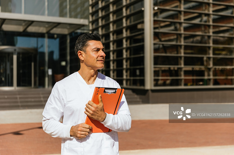 穿白色工作服的男人站在现代建筑外图片素材