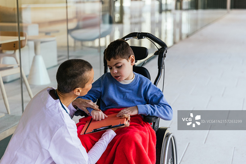 女医生与坐轮椅的男孩交谈图片素材