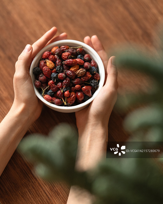 女性手中的一碗干玫瑰果，用于制作维生素茶。图片素材