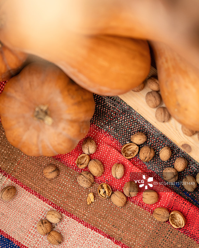 完整的南瓜和切碎的核桃在自制地毯上，秋收，手工帆布，坚果壳和果肉，静物，乡村风格，条纹背景，顶部视图，柔焦图片素材