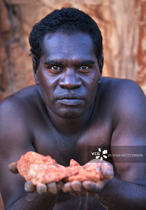 澳大利亚北领地东阿纳姆地区Bawaka家园附近，一位手持红色岩石的澳大利亚土著男子肖像图片素材