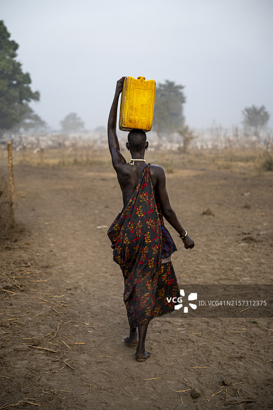 非洲南苏丹蒙达里部落妇女头顶水罐图片素材