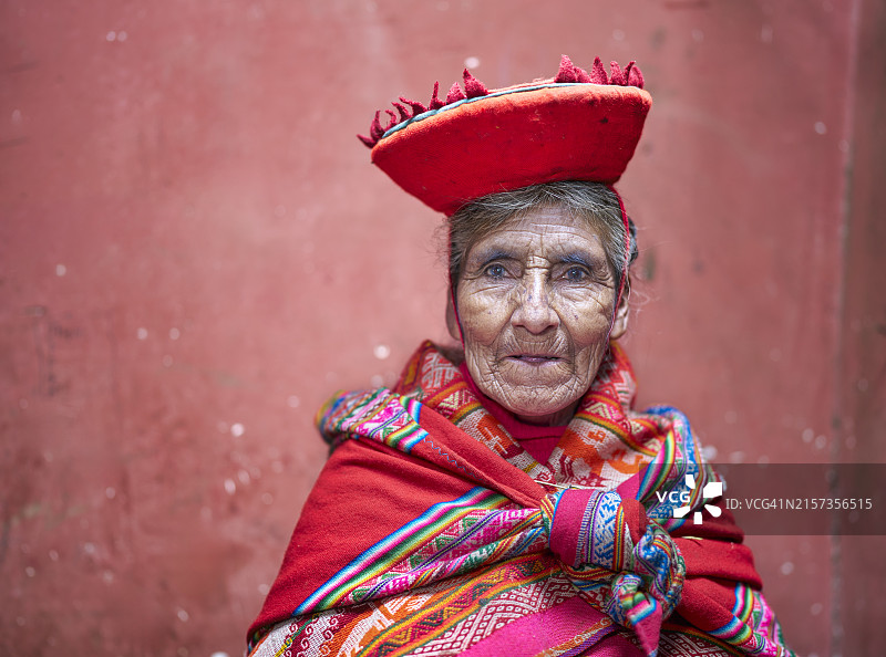 秘鲁安第斯山脉库斯科附近，年长的克丘亚族妇女的红色背景影棚肖像照，留有文案空间图片素材