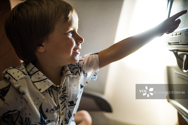 可爱男孩在飞机上使用电子设备屏幕图片素材