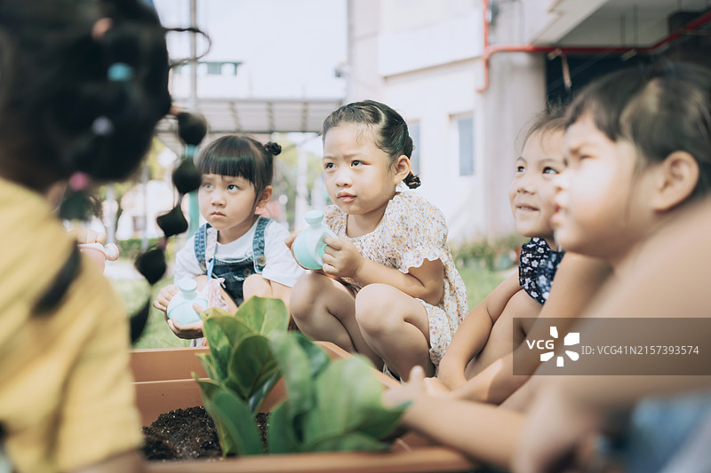 幼儿园老师在苗圃里教孩子们关于植物的知识图片素材