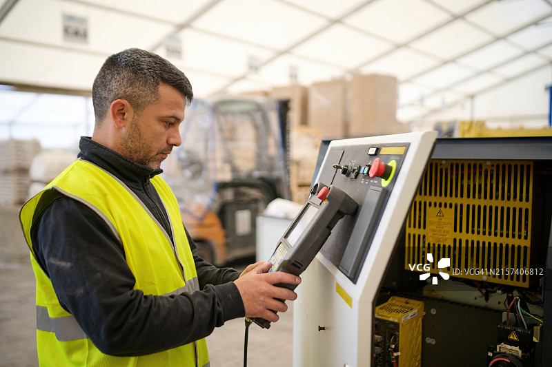 身穿黄色马甲操作机器的男人图片素材