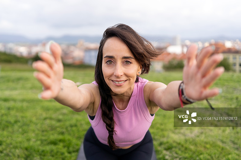 瑜伽教练在户外做椅子姿势伸展时微笑图片素材
