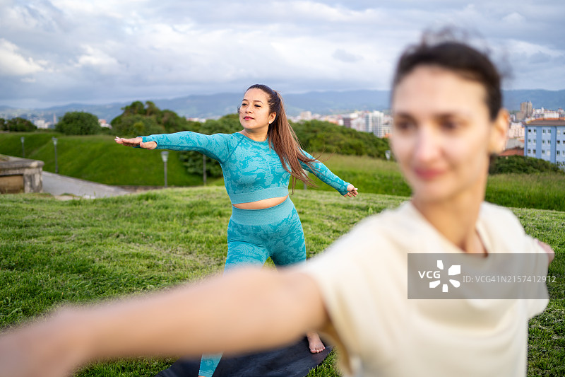 在城市公园户外练习瑜伽战士姿势的女人图片素材