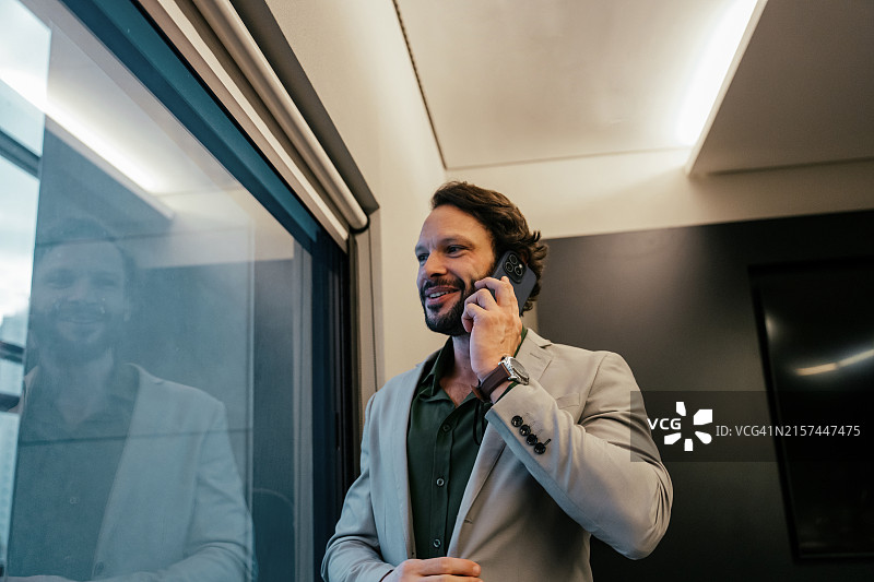 对着窗户用手机交谈的商人图片素材