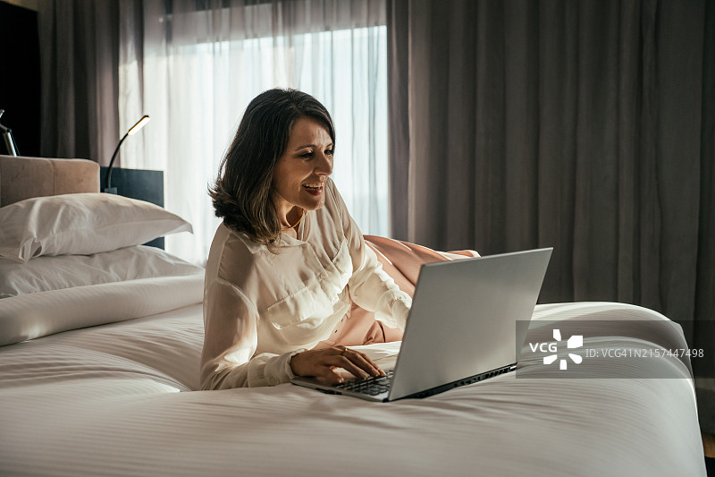 在酒店房间使用笔记本电脑的商务女性图片素材
