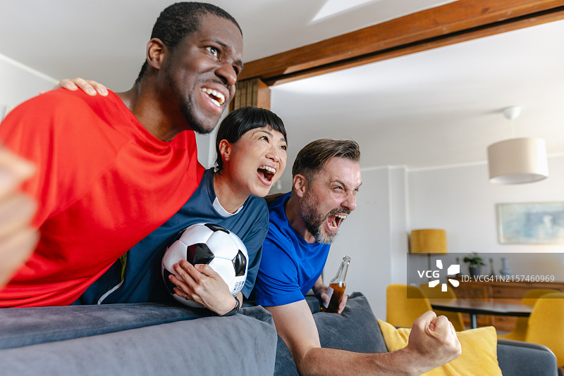 朋友们在电视上看足球比赛时欢呼图片素材
