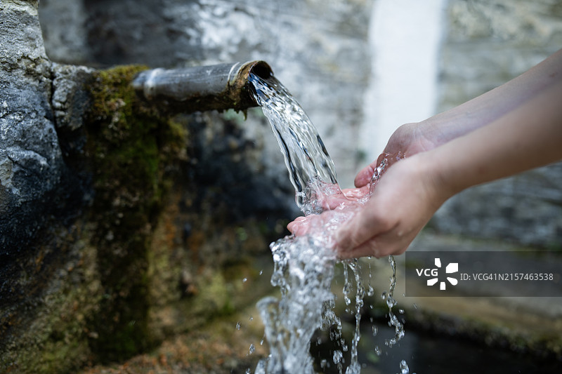 手部特写，触摸饮水机流出的水。图片素材