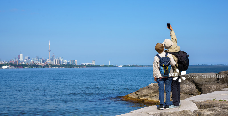 在多伦多城市地标旁使用智能手机的快乐老年夫妇图片素材
