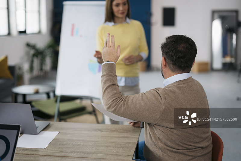 在办公室商务演示中举手提问的商人图片素材