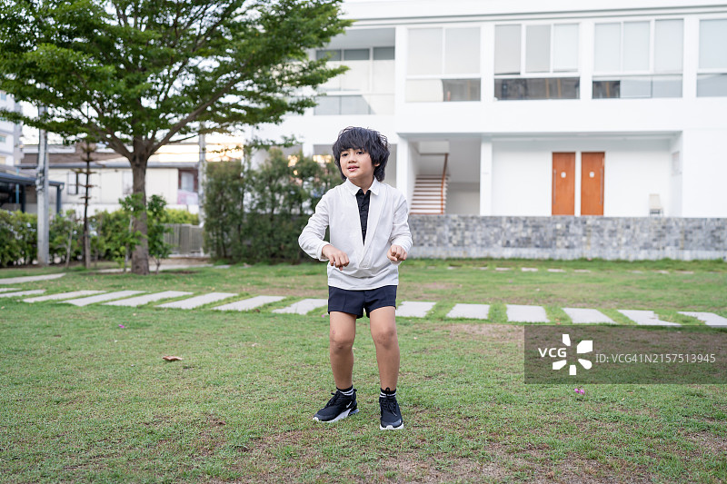 在幼儿园花园里伴随音乐跳舞的亚洲小学生图片素材
