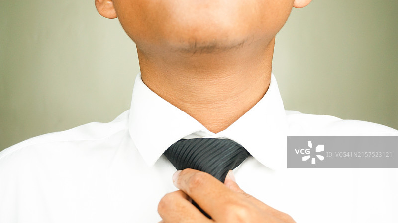 系着黑色领带，穿着白色正装衬衫准备上班的男人图片素材