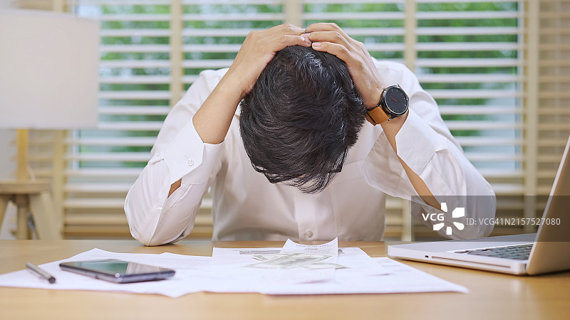 压力大的男人双手抱头坐在办公桌前图片素材
