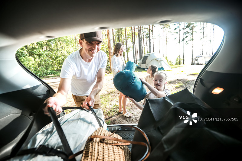 自然短途旅行：快乐的孩子们在河边松树林营地与父母一起打开汽车图片素材