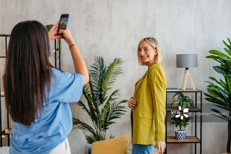 年轻女人在客厅为女性朋友拍照图片素材