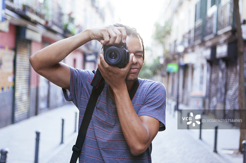 在街上拿着照相机的年轻非洲男子图片素材