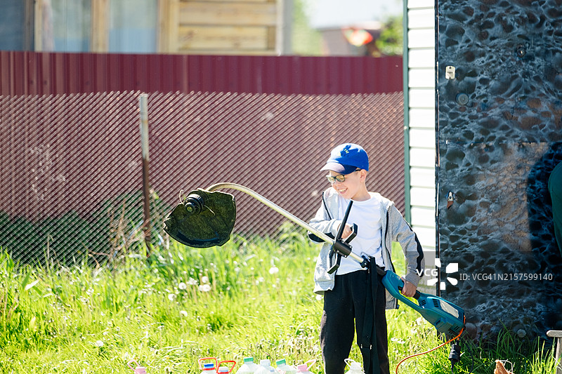 在村庄用割草机工作的小男孩图片素材