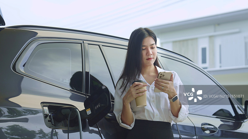 正在等待电动汽车充电的女人图片素材