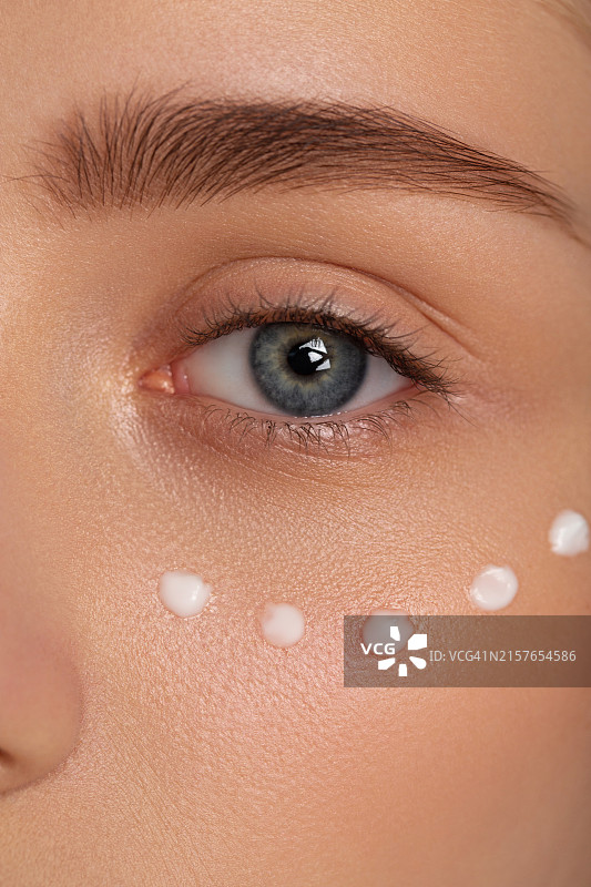 在脸上涂抹护肤霜的美丽女孩图片素材