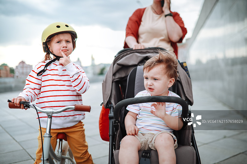 中国城市滨水区：大码妈妈与两个孩子，推着婴儿车和平衡车散步图片素材