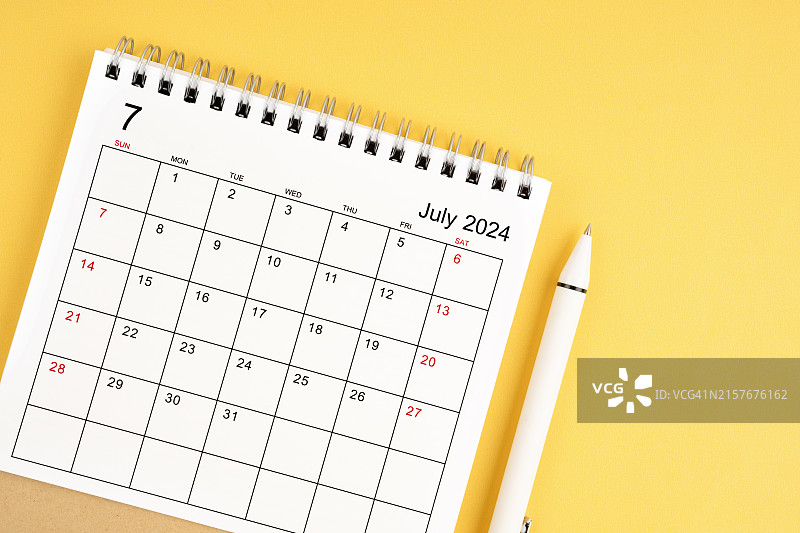 2024年7月黄色背景上的台历和笔图片素材
