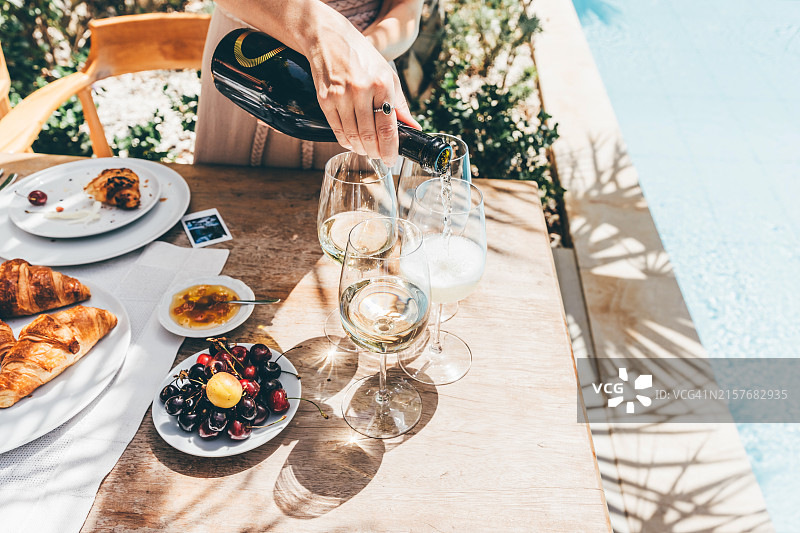 在聚会上，女人倒白葡萄酒图片素材